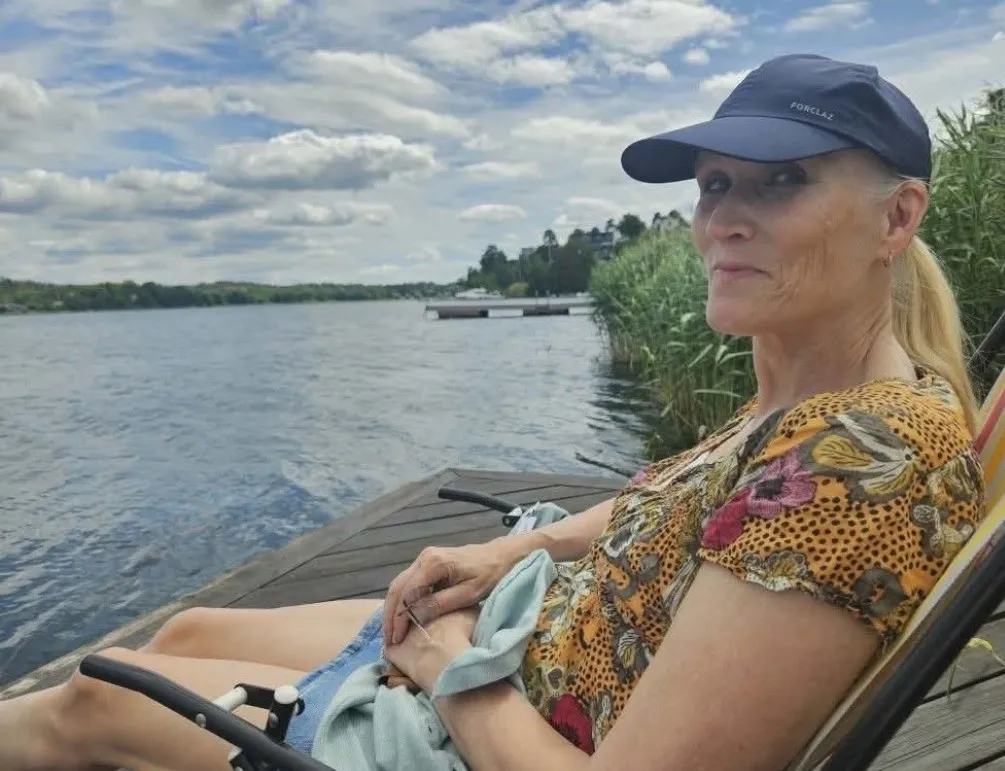 Bild på Anette som sitter i en solstol på en brygga vid en sjö